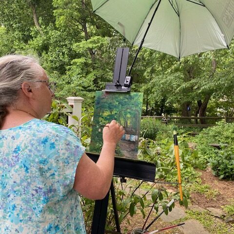 A painter working on her painting in a garden