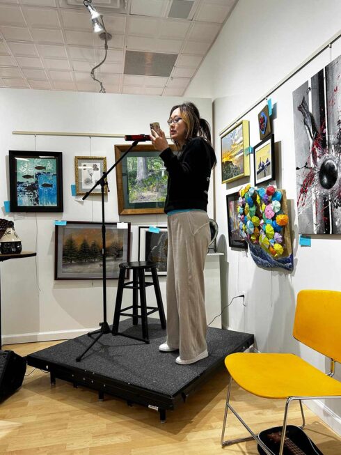 Image showing an artist performing on a small stage in the corner during an open mic night in the gallery
